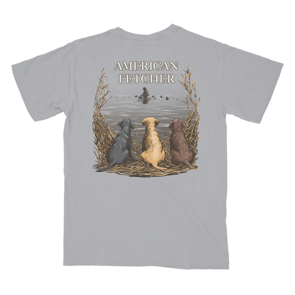 Graphite shirt with back says american fetcher and duck hunter in the water with 3 dogs watching.