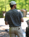 Man wearing camo shirt and white hat showing back of tee shirt. 