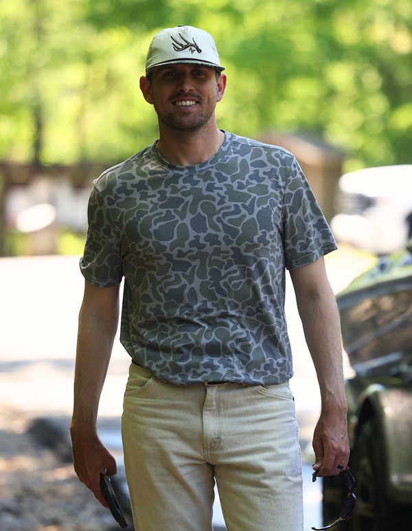 Man wearing camo shirt and white hat with antler.