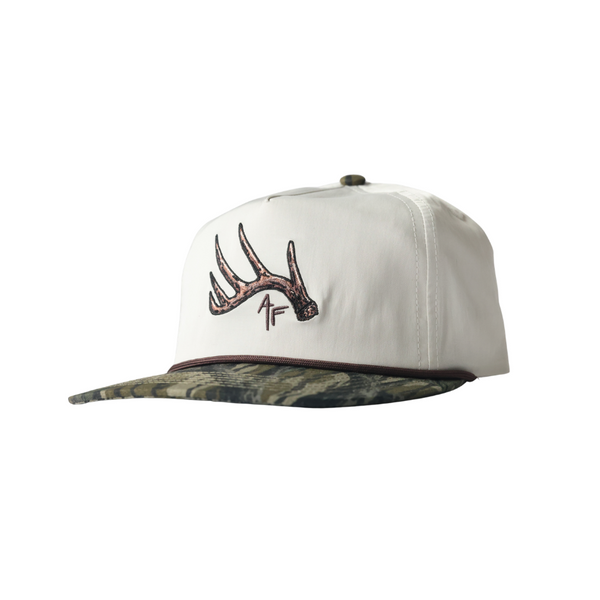 White cap with camouflage bill and deer antler logo on a white background