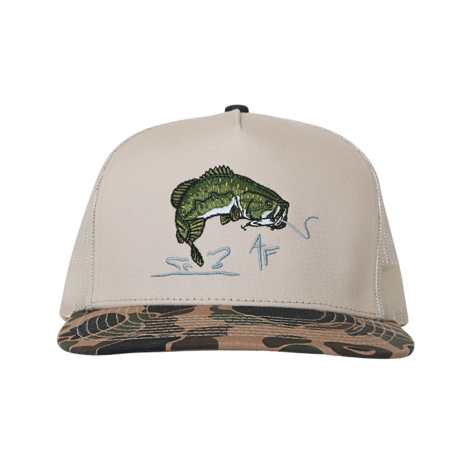 A beige trucker-style cap with a camouflage-patterned visor and a green bass fish graphic embroidered on the front, shown against a plain white background.