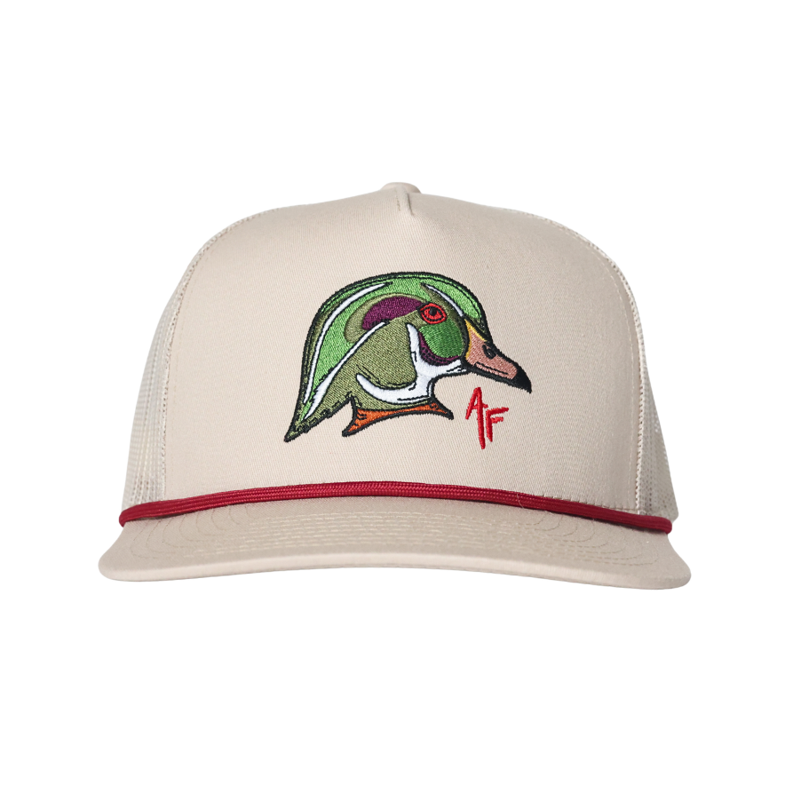 A beige trucker-style cap with a red brim stripe and a colorful embroidered wood duck head patch on the front, set against a plain white background.
