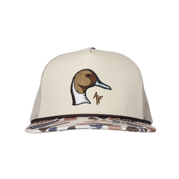 A beige trucker-style cap with a brown and pintail duck head embroidery on the front and a camouflage-patterned visor, shown against a plain white background.