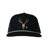 A black trucker hat with a curved brim, featuring an embroidered deer skull with antlers in white, gold, and brown on the front panel, and a thin light gray rope detail along the edge of the brim.