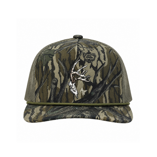 A camouflage trucker cap with a Mossy Oak tree-bark pattern in shades of green, brown, and beige, featuring a white embroidered deer skull graphic and a small 'AF' brand logo on the front.