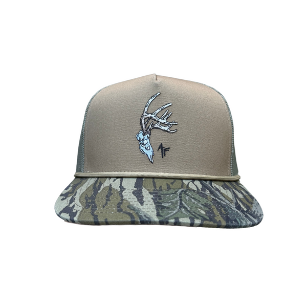 A baseball cap with a tan front panel and a camouflage-patterned visor, featuring an embroidered deer head with antlers and a small black 'AF' logo on the front.