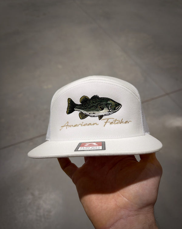 White cap with fish design and 'American Fletcher' text held by a hand on a gray surface